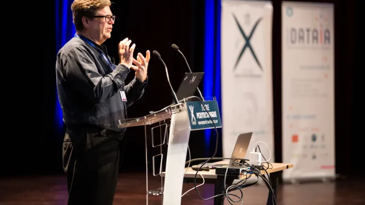 Yann LeCun speaking at a lectern at École Polytechnique in 2018. Photo by Jérémy Barande / École polytechnique, CC BY-SA 2.0, via Wikimedia Commons.